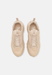 Beige sneakers i mesh och syntetmaterial med texturerad ovandel, snören och en dragflik på hälen. Böjda designelement.