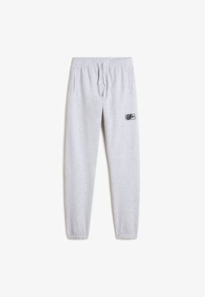 Pantaloni da felpa grigi in cotone con vita elastica, cordoncino, tasche laterali e un piccolo logo nero sulla coscia superiore. I polsini sono aderenti.