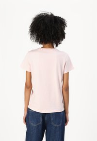 Tricou din bumbac roz deschis, cu mâneci scurte și guler rotund. Potrivit cu pantaloni din denim albastri. Design simplu, textură moale, fără decorațiuni.