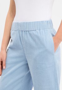 Φωτεινό γαλάζιο παντελόνι κορδούρα με υφή, ελαστική μέση και πλευρικές τσέπες. Διαθέτει διακριτικές κάθετες ρίγες.