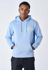Sudadera azul clara hecha de tela suave, con bolsillo delantero, cordones y detalle de logo bordado en el pecho.