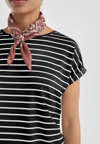 Camiseta a rayas en blanco y negro con mangas cortas dobladas, combinada con una bufanda decorativa de rosa empolvado con un patrón de cachemir.
