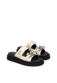 Sandali scivolati in pelle verniciata bianca con due ampie cinghie, impreziositi da gemme trasparenti e hardware in argento, con una soletta nera.