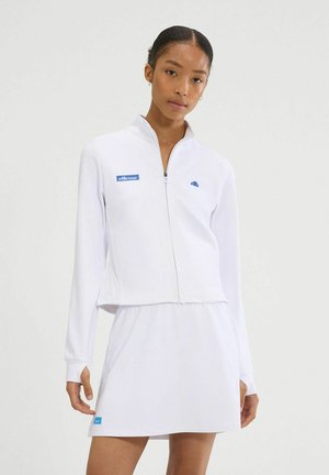 Chaqueta blanca con cremallera, de mangas largas y diseño cropped, combinada con una falda blanca. Presenta acentos de logotipo azul en ambas prendas.