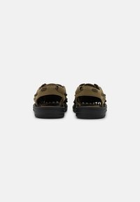 Olivengrønne sandaler med sorte såler, der har flere stropper, en tekstureret sål og åben rygdesign for åndbarhed og komfort.
