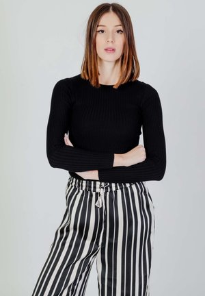Top nero a maniche lunghe a coste abbinato a pantaloni a gamba larga a righe bianche e nere con vita elastica e cordoncino.