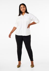 Valge nööpidega särk üles keeratud käistega, kombineeritud mustade kitsaste pükstega, mille pahkluudes on kuldsed nööpide aktsendid. Pehme kangas, klassikaline disain.