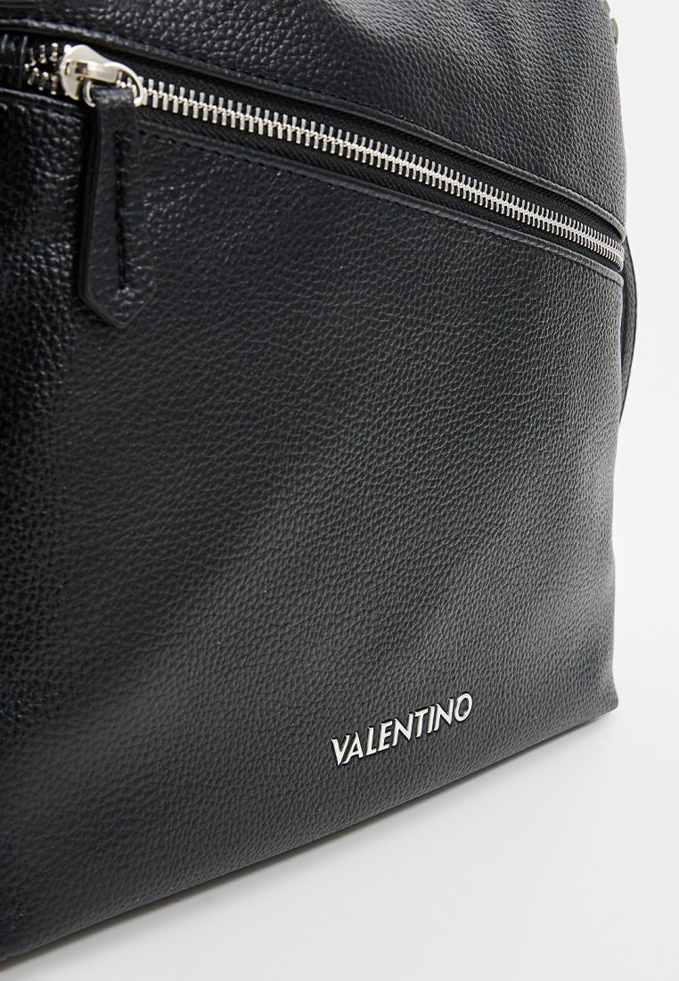 Schwarze Lederhandtasche mit strukturiertem Finish, versehen mit einem silbernen Reißverschluss oben und einem kleinen Fach. Markenname "VALENTINO" in Silber geprägt.