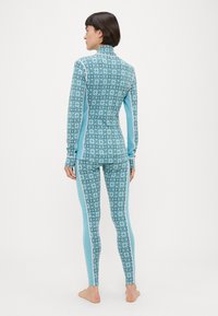 Σετ αθλητικής ένδυσης με μπλε σχέδιο που περιλαμβάνει ψηλό γιακά, μακριά μανίκια και εφαρμοστά κολάν με γεωμετρικό σχέδιο και αντίθετες πλευρικές ρίγες.