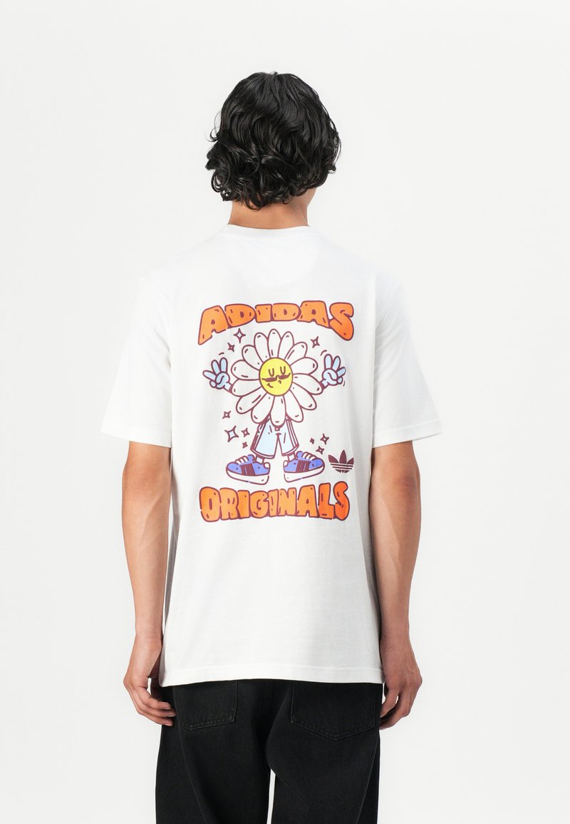 White cotton t-shirt featuring a colorful graphic of a smiling flower character with the text "ADIDAS ORIGINALS" prominently displayed.