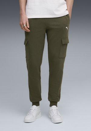 Olivengrønne cargo sweatpants lavet af blødt stof, med to sidelommer og en tætsiddende manchet ved anklen. Bærer dem med hvide sneakers.