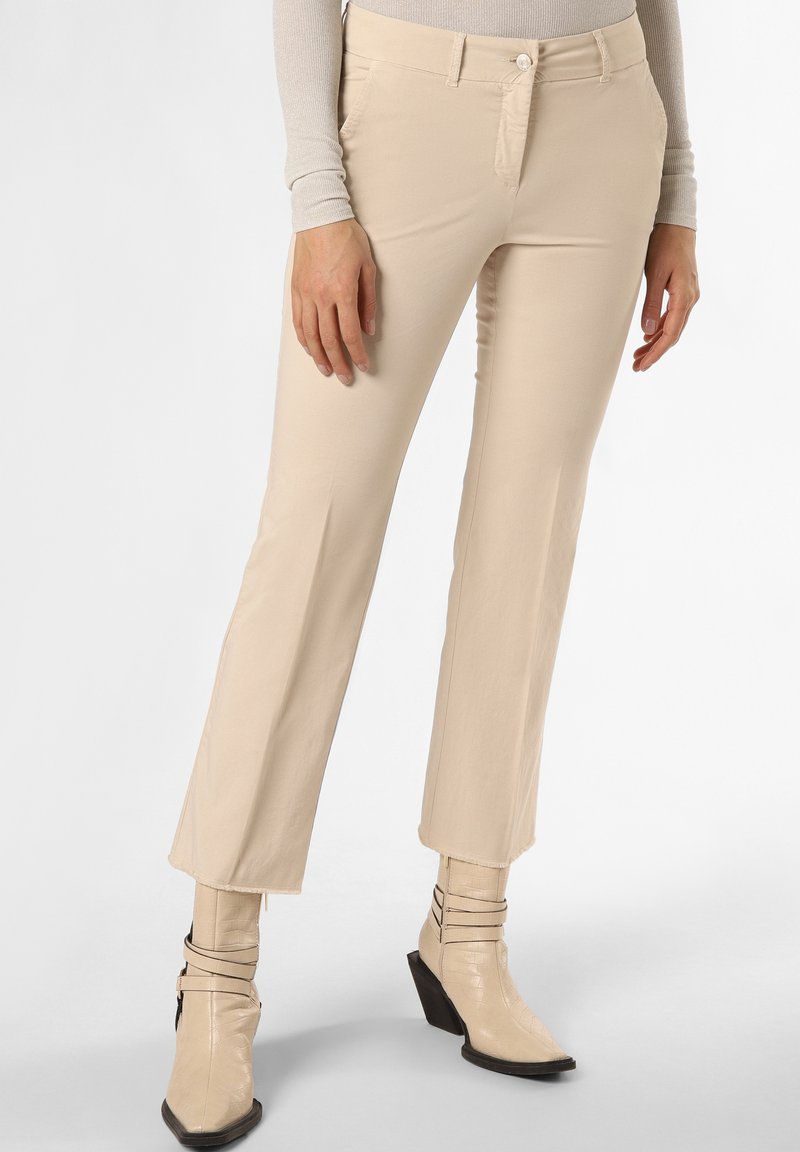 Beige gerade geschnittene Hosen aus glattem Stoff, mit Vorderhosen Taschen und einem dezenten Stich-Detail. Kombiniert mit beigen Stiefeletten mit Absatz.