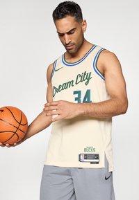 Krémové basketbalové tričko s nápisom "Cream City" v zelenej skrypte a číslom "34" v modrej. Obsahuje logo Nike a štítok NBA na boku.