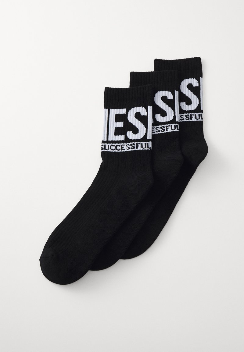 Meias de crew em algodão preto, com o texto branco "SUCEDIDO" e um design canelado, empilhadas em um conjunto de três.