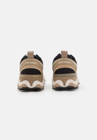 Black and beige sneakers with mesh detailing, prominent back support, and a wavy cream and gray sole. Logo on the heel.