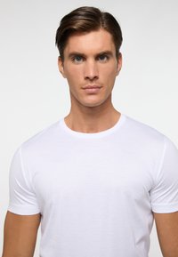 Witte T-shirt met korte mouwen, gemaakt van lichte stof. Heeft een ronde halslijn en een getailleerd ontwerp, met een zachte textuur en een basic stijl.