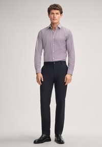 Camicia a quadri viola chiaro con colletto, maniche lunghe e chiusura a bottoni, abbinata a pantaloni scuri e scarpe in pelle nere.