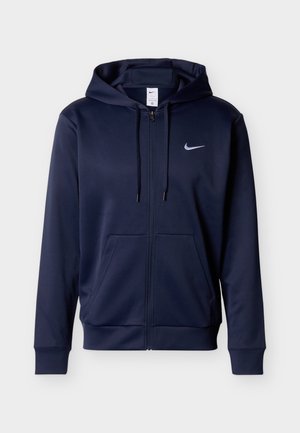 Tamnoplavi duks na patent s prednjim džepovima, podesivim vezicama na kapuljači i malim bijelim Nike swoosh logom na lijevoj strani prsa.