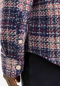 Audinė marškiniai su tekstūriniu raštu tamsiai mėlynos, raudonos ir baltos spalvų; su mygtukinėmis rankovėmis ir hemu, kuris šonuose yra trumpesnis.