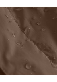 Tissu imperméable marron avec une texture lisse, présentant de petites gouttes d'eau à la surface, couture visible le long de la couture.