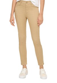 Beige slim-fit hlače z gladko teksturo, z zadrgo in gumbom za zapiranje, sprednjimi žepi in krojem po meri. Nosi se z belimi supergami.