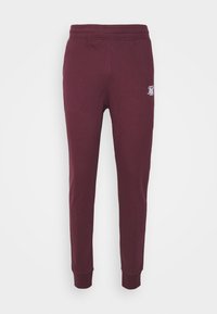 Bordeauxfärgade sweatpants med en slät textur, elastisk midja och manschetter vid anklarna. Har en vit logotyp på vänster lår.