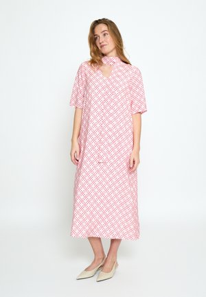 Frau trägt ein midi-kariertes Kleid in Rosa und Weiß mit kurzen Ärmeln und Schlitz am Ausschnitt, kombiniert mit spitzen beigen Slingback-Absatzschuhen.