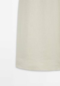 Robe en lin de couleur beige clair ; coupe droite et ourlet simple. Texture douce avec des coutures minimalement visibles et sans motifs.