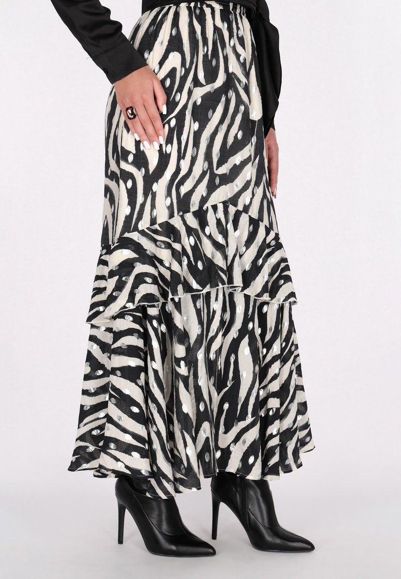 Gestufter Maxi-Rock mit schwarz-weißen Zebra-Streifen und Rüsche am Saum, aus leichtem Stoff, kombiniert mit schwarzen spitzen High Heels.