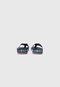 Flip-flops bleu marin cu o talpă texturată, având un design cu două bretele și accente albe de-a lungul marginilor. Logo imprimat pe talpa interioară.
