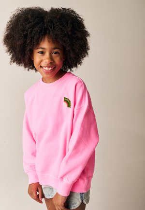 Lys pink sweatshirt med lange ærmer, ribbede manchetter og en lille, flerfarvet regnbuebroderi på brystet.