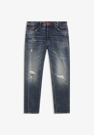 Ciemnoniebieskie jeansy z efektem przetarć, posiadające rozdarcia i blaknięcia, klasyczny fason z pięcioma kieszeniami oraz zapięcie na guzik w pasie.