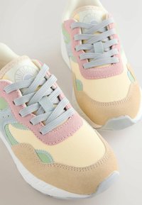 Baskets multicolores combinant du synthétique et du daim en rose, vert et jaune, avec des accents texturés et des lacets gris.