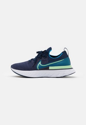 Chaussure de course Nike bleu marine et sarcelle avec des accents verts, une semelle blanche, un design à lacets et un matériau tricoté respirant.