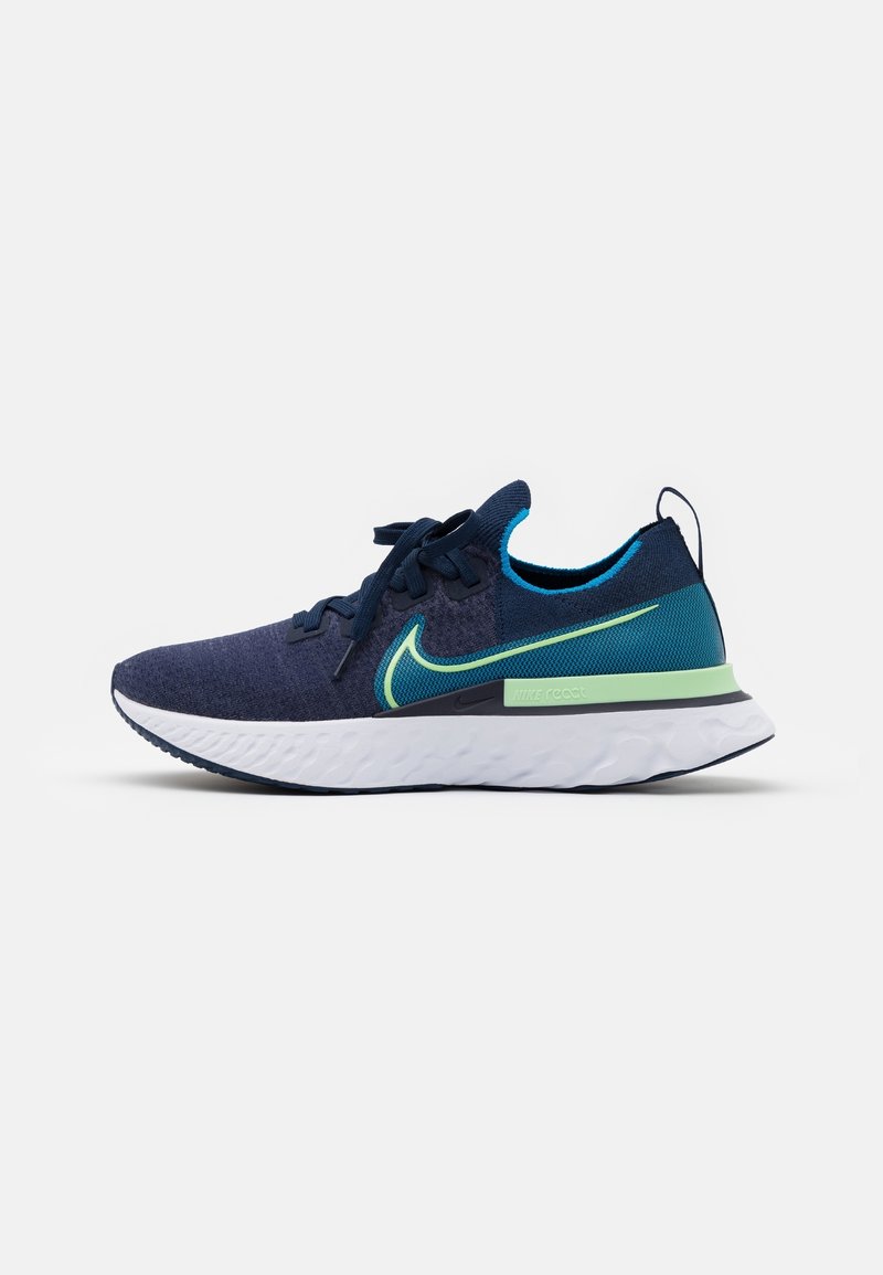 Chaussure de course Nike bleu marine et sarcelle avec des accents verts, une semelle blanche, un design à lacets et un matériau tricoté respirant.