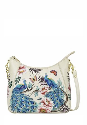 Handtasche aus cremefarbenem synthetischem Material mit Pfauenmotiv, das lebendige blaue Pfauen und florale Designs zeigt, ergänzt durch einen goldenen Kettenriemen.