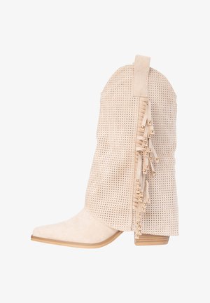 Bota vaquera de ante beige con parte superior perforada, flecos decorativos con cuentas doradas, punta puntiaguda y tacón bajo apilado.