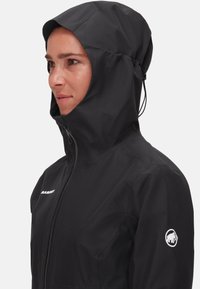 Schwarze wasserdichte Jacke mit passgenauer Kapuze, Reißverschluss vorne und Logo am Ärmel. Hergestellt aus strukturiertem Material, entwickelt für den Einsatz im Freien.