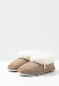 Brown suede slippers featuring a fluffy white faux fur cuff, rounded toe design, and stitched detailing along the edges. Non-slip sole.