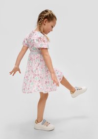 Floral dress with short puff sleeves in pink, purple, and green, featuring a fitted waist and flowing skirt; paired with white, multi-strap sneakers.