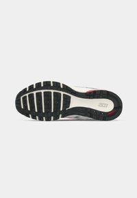 Nike-Sneaker-Sohle mit schwarzem Gummitreter, grauen und roten Akzenten, strukturierten Oberflächen und sichtbarem Logo in der Nähe der Ferse.