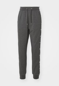 Graue Jogginghosen mit einem Kordelzugbund, schmal zulaufenden Beinen und Druckknopfdetails an den Seiten. Hergestellt aus weichem, strukturiertem Stoff.