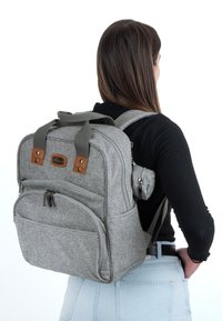 Grijze stoffen rugzak met twee bovenhandvatten, meerdere ritssluitingen, leren accenten en verstelbare schouderbanden. Textuur oppervlak met een gestructureerd ontwerp.