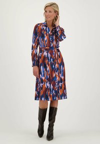 Shirtdress in een kleurrijke print met tinten blauw, oranje en paars; lange mouwen, knoopsluiting aan de voorkant, ceintuur op de taille, tot de knie.