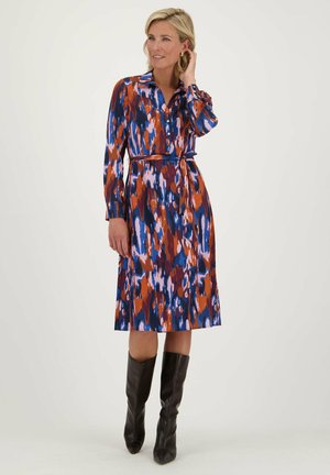 Robe chemise dans un imprimé coloré avec des nuances de bleu, orange et violet ; manches longues, devant à boutons, taille ceinturée, longueur genoux.