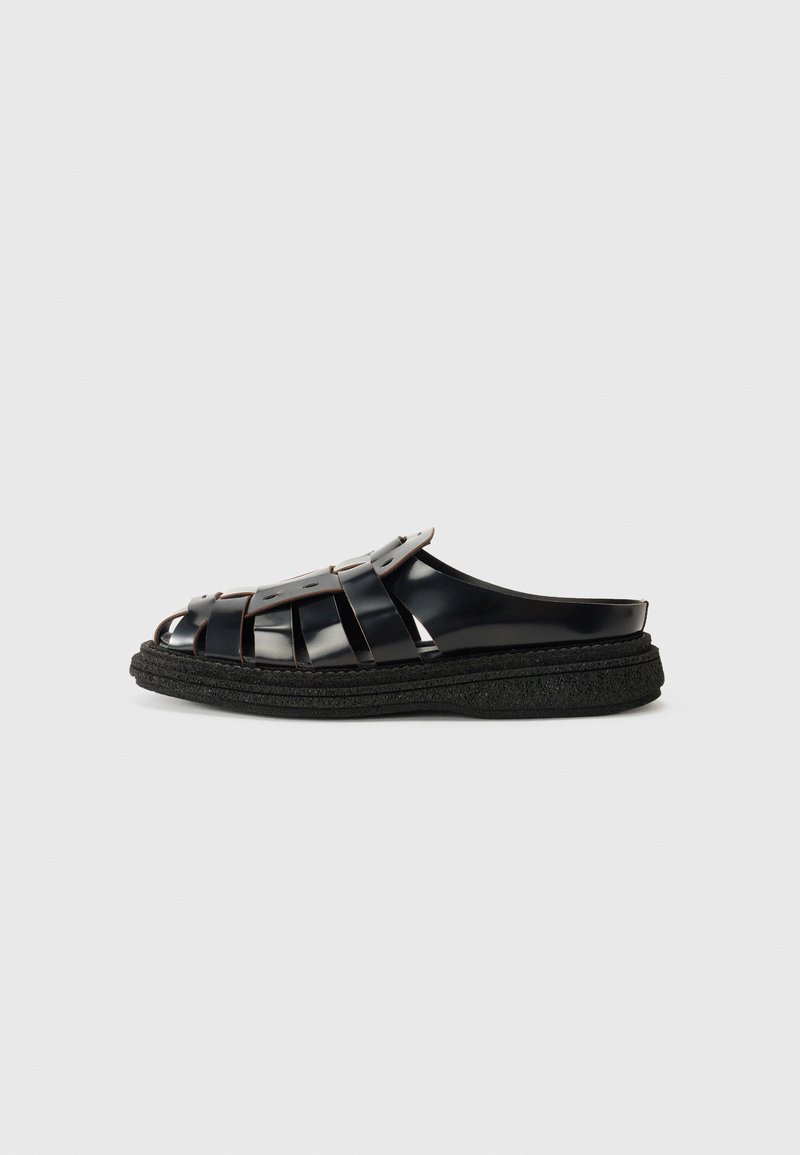 Pantof de plastic negru, cu design dintr-o bandă împletită, având o talpă groasă, texturată, de culoare neagră. Fără catarame sau embellismente vizibile.