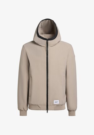 Bež kapuutsiga jakk, millel on musta äärisega krae, ees tõmblukk ja küljetaskud. Omab ribakudumisega varrukaotsi ja logosilti allääres.