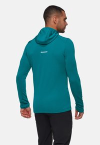 Teal lange mouw hoodie met een aansluitend ontwerp, voorzien van een verhoogde kraag en logo op de achterkant. Zachte, gladde textuur geschikt voor buitengebruik.