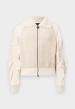 Strick- und Web-Jacke in Creme mit Reißverschluss, gerippter Kragen und Ballonärmeln. Verfügt über eine strukturierte Vorderseite und glatten Stoff an den Seiten.