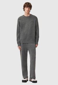 Grauer Fleecepullover und passende Hose mit lockerem Sitz. Der Pullover hat einen Rundhalsausschnitt und eine dezente Logo-Stickerei.